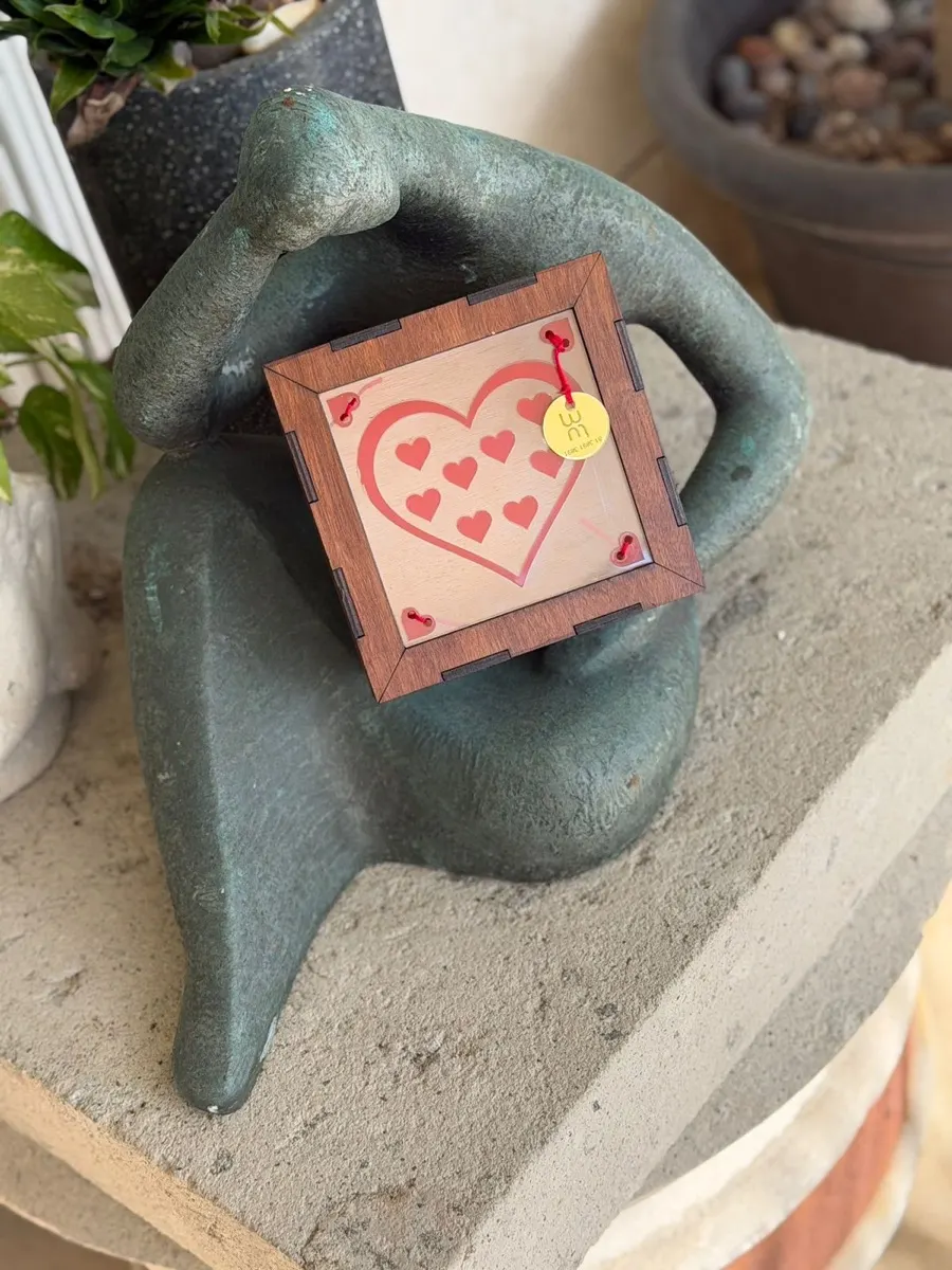 Marco corazón de madera con corazones de acrílico sobre escultura de bronce